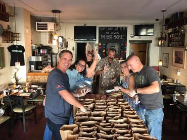 Group behind table of containers):The crew gathering for a quick photo behind rows of carefully prepared, ready-to-go community meals.