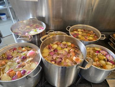 Large pots on stove):Hearty, Potatoes simmering on the stove, made from scratch to feed the neighborhood.