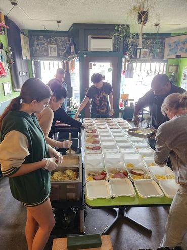 An impressive assembly line loading up rows of warm, fresh community meals.